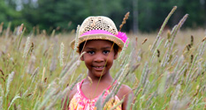 little girl playing in a field in tall grass