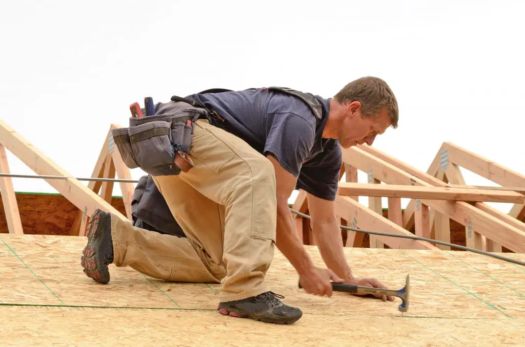 Framing contractor installing roof sheeting over rafters on a new commercial residential construction project